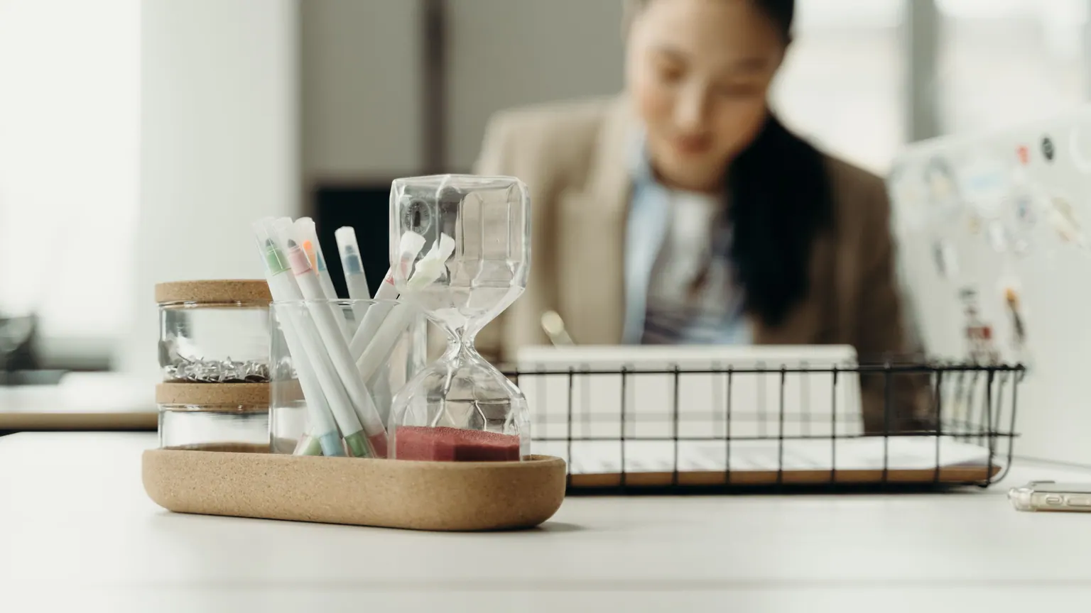 Materiais de planejamento organizados sobre a mesa com uma professora ao fundo