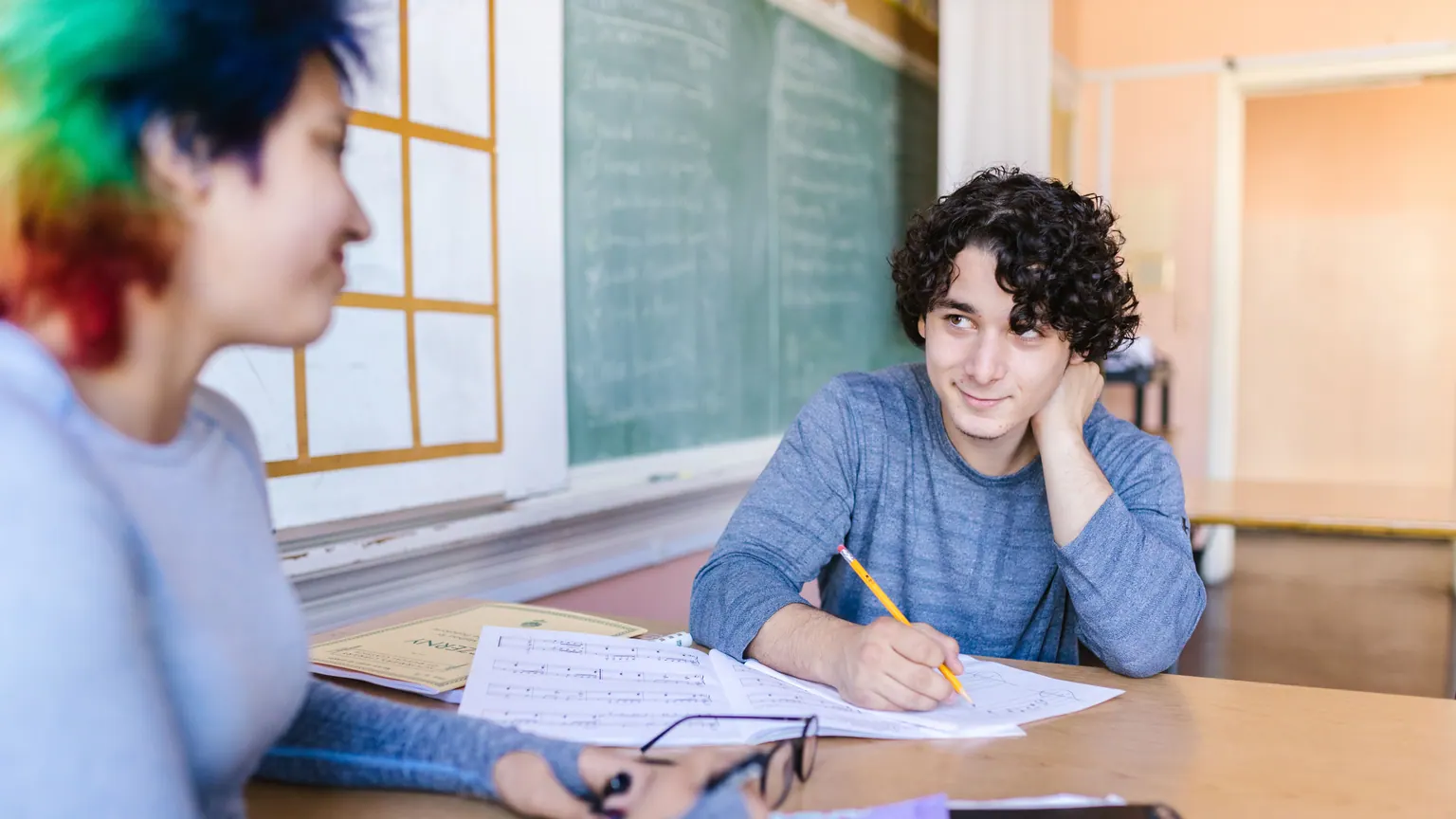 Estudante realiza uma atividade escrita com expressão confiante em sala de aula
