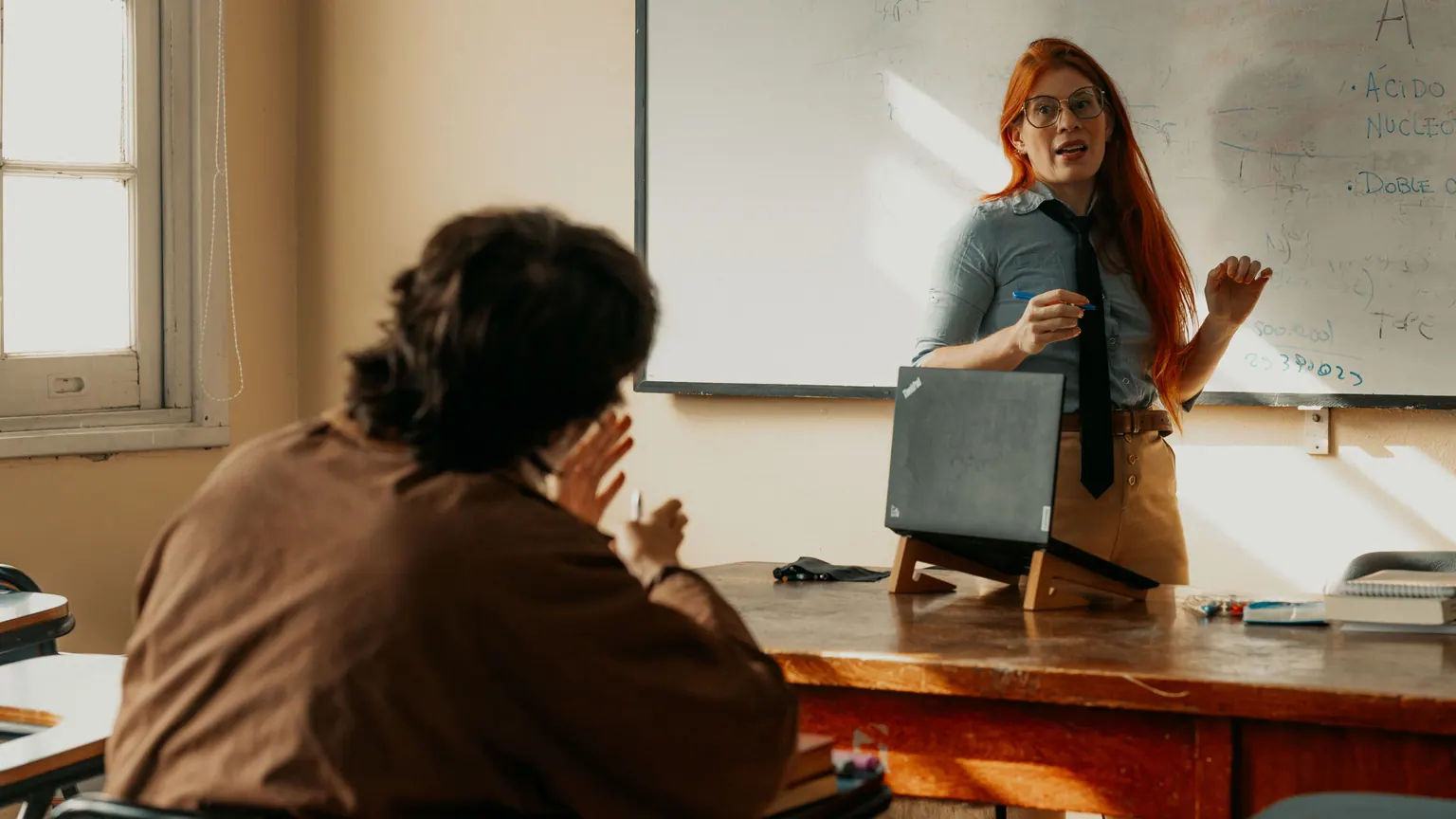 Professora apresenta uma atividade diante de um grupo em sala de aula