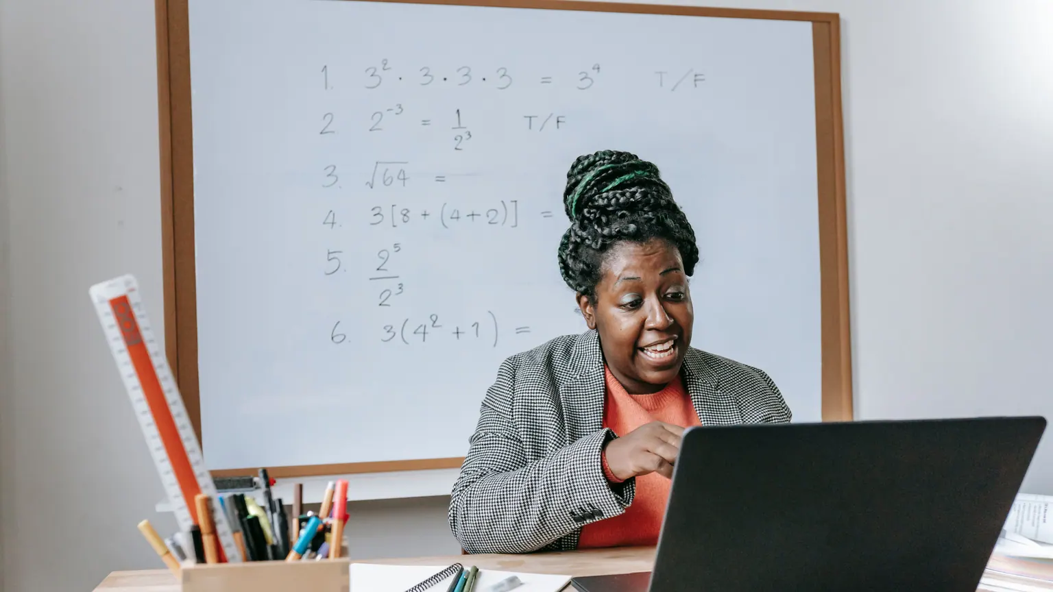 Professora trabalha com computador e materiais em uma sala de aula