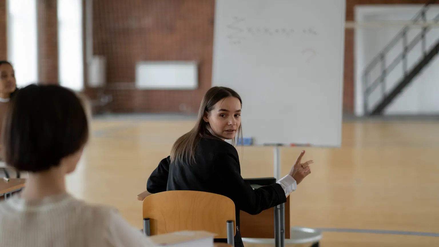 Professora aponta para um quadro durante uma conversa em sala de aula